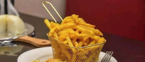 A basket of French fries on a plate with a fork beside it.