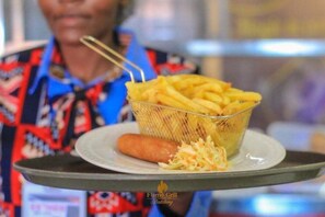 A tray with a basket of French fries, a sausage, and coleslaw.