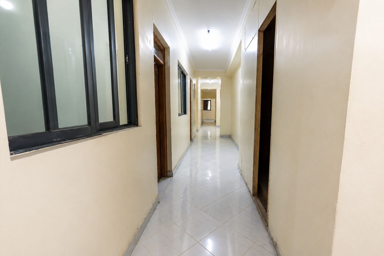 A corridor with doors on both sides, leading to rooms.