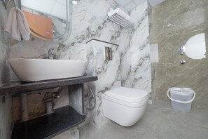 Une salle de bain avec un lavabo blanc, des toilettes et un espace douche.