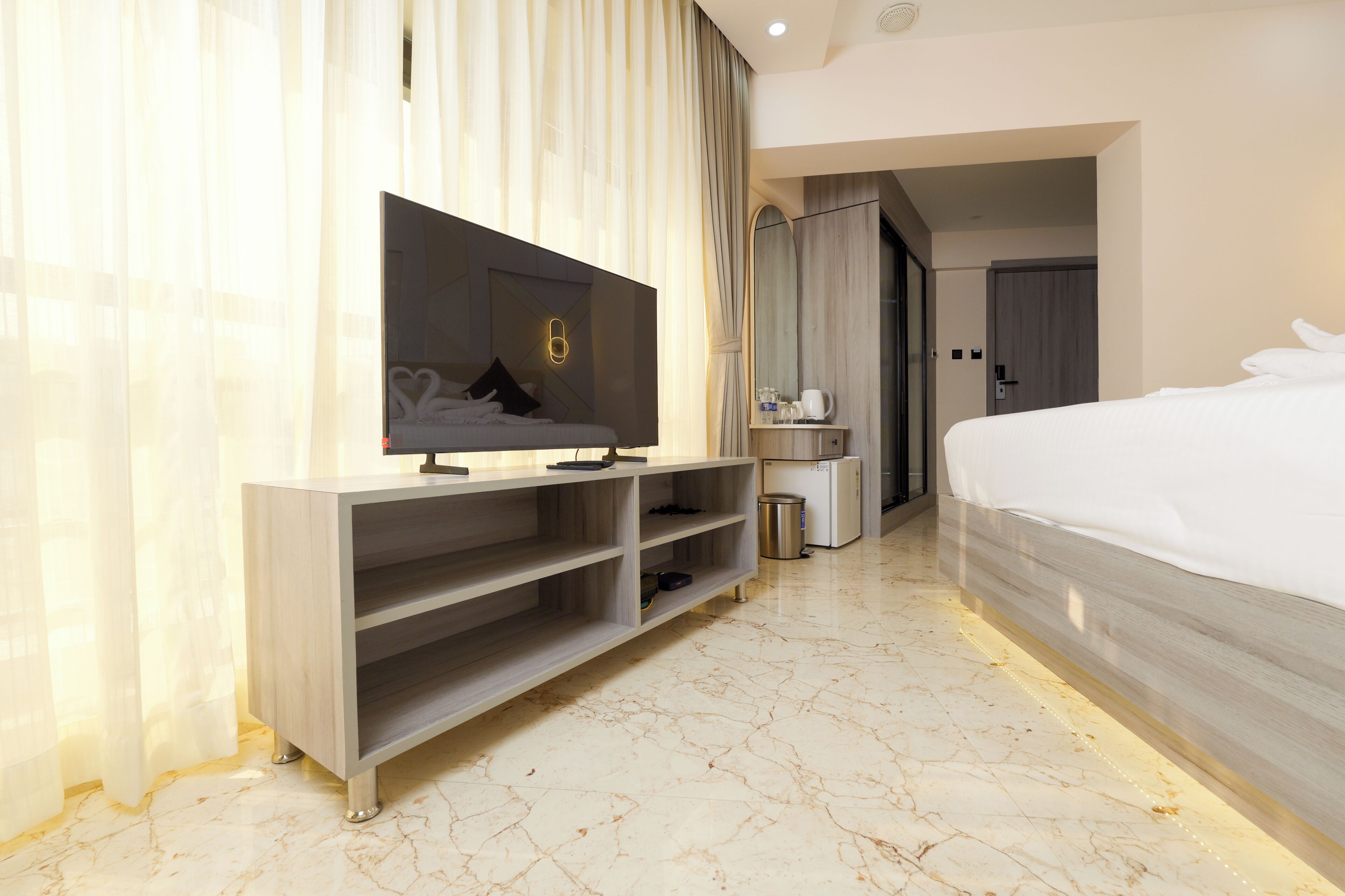 Une chambre d’hôtel avec un lit, une télévision, un minibar et une salle de bain, le tout visible à travers une porte ouverte.