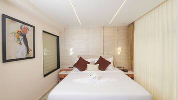 Quarto de hotel com uma cama grande, um quadro na parede e uma mesa de cabeceira com um telefone.