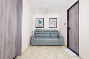 Una habitación con un sofá gris, un ventilador de techo y dos frases motivacionales enmarcadas en la pared.