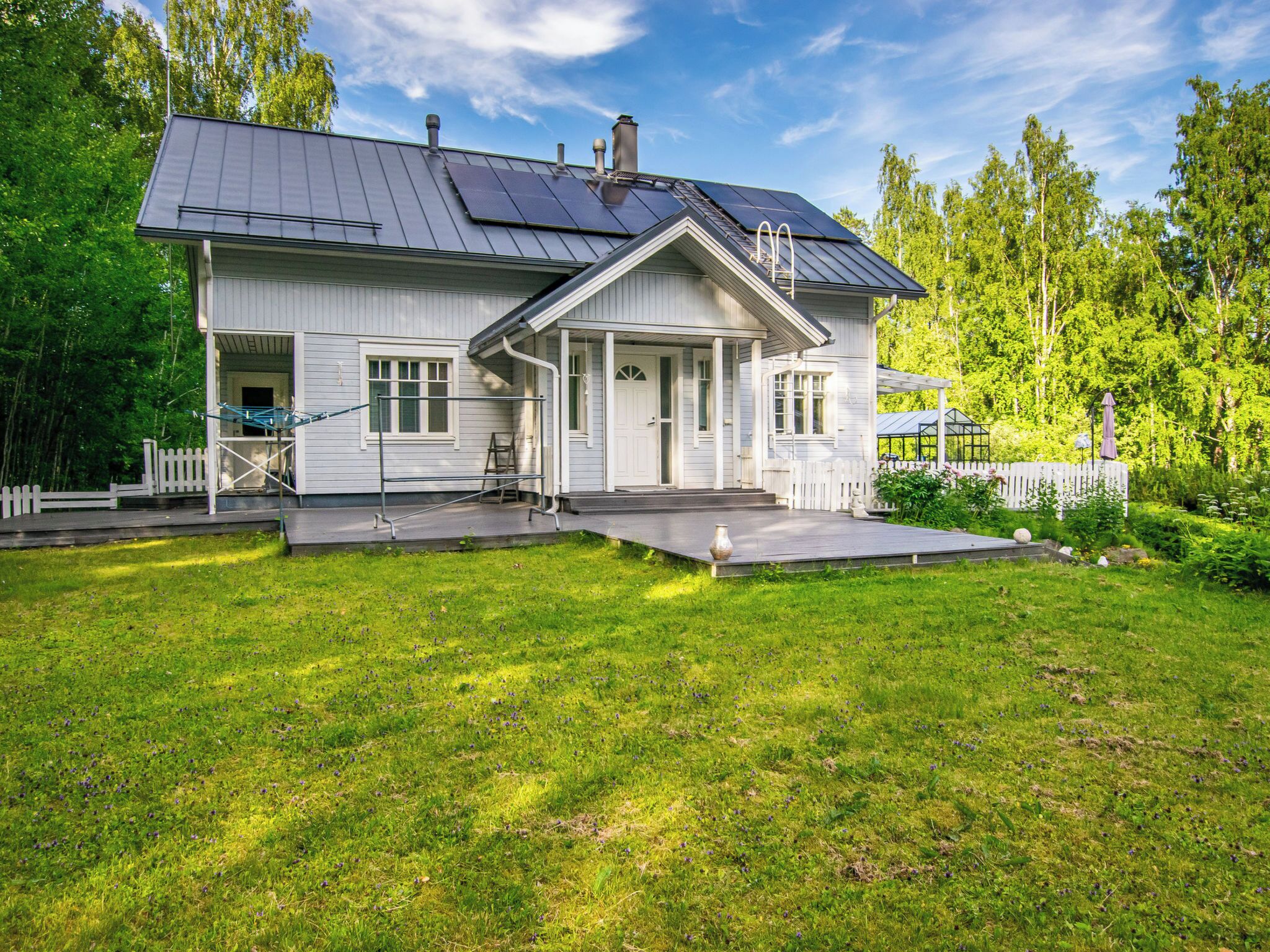 Una casa a due piani con un portico, una veranda coperta e un giardino recintato.
