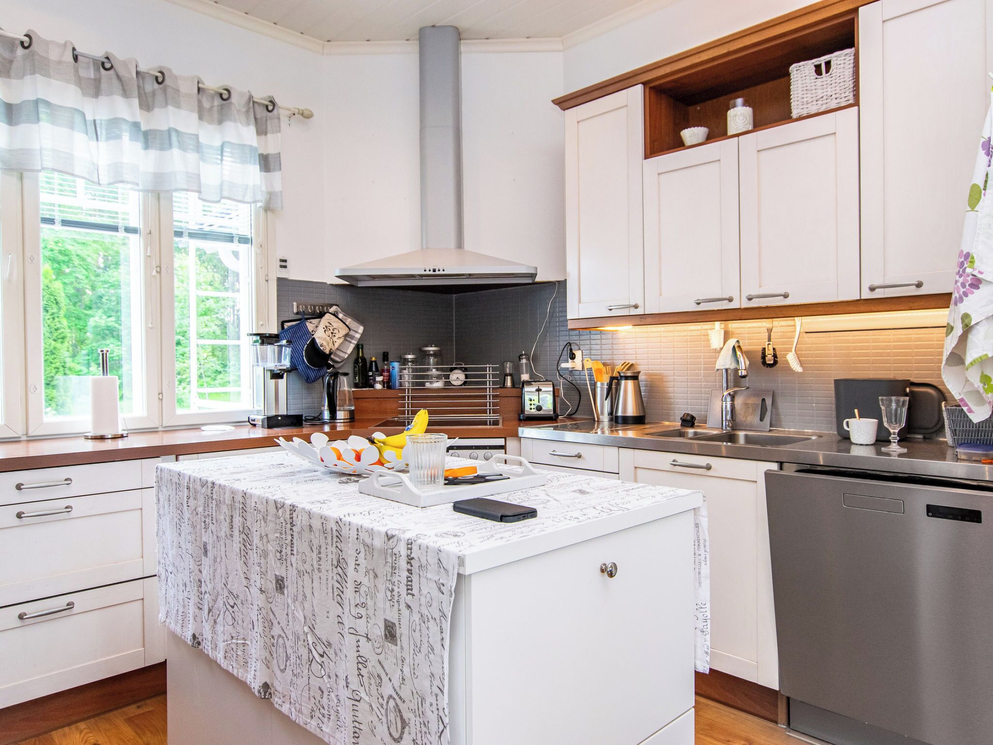 A modern kitchen with white cabinetry, a central island, and a stainless steel dishwasher.