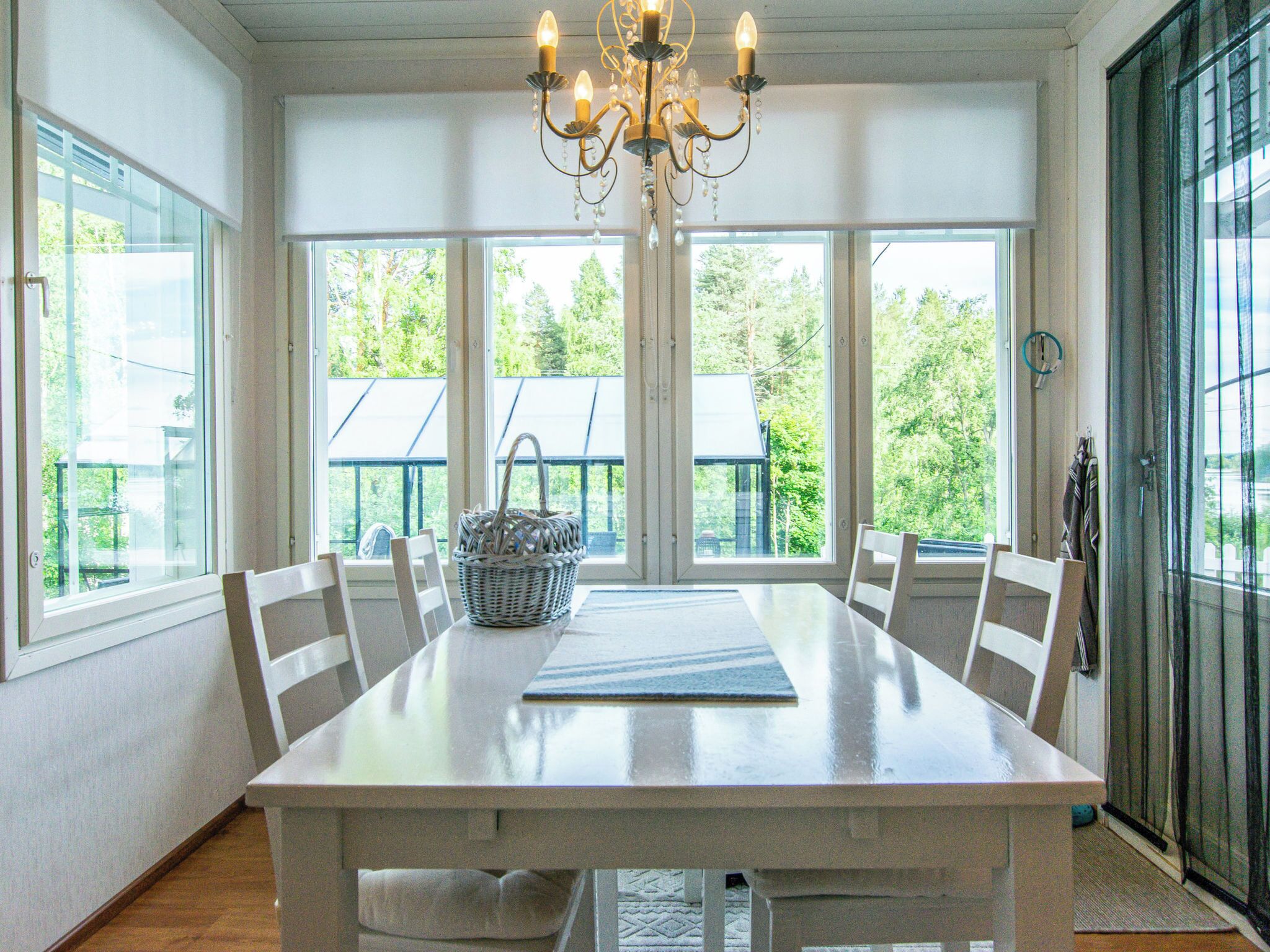 Une salle à manger avec une grande table, des chaises, un lustre et de grandes fenêtres.