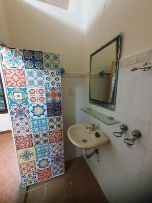Ein Badezimmer mit gefliesten Wänden, einem Waschbecken, einem Spiegel und einer Duschkabine.