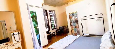 A bedroom with a bed, a desk, a chair, and a window with curtains.