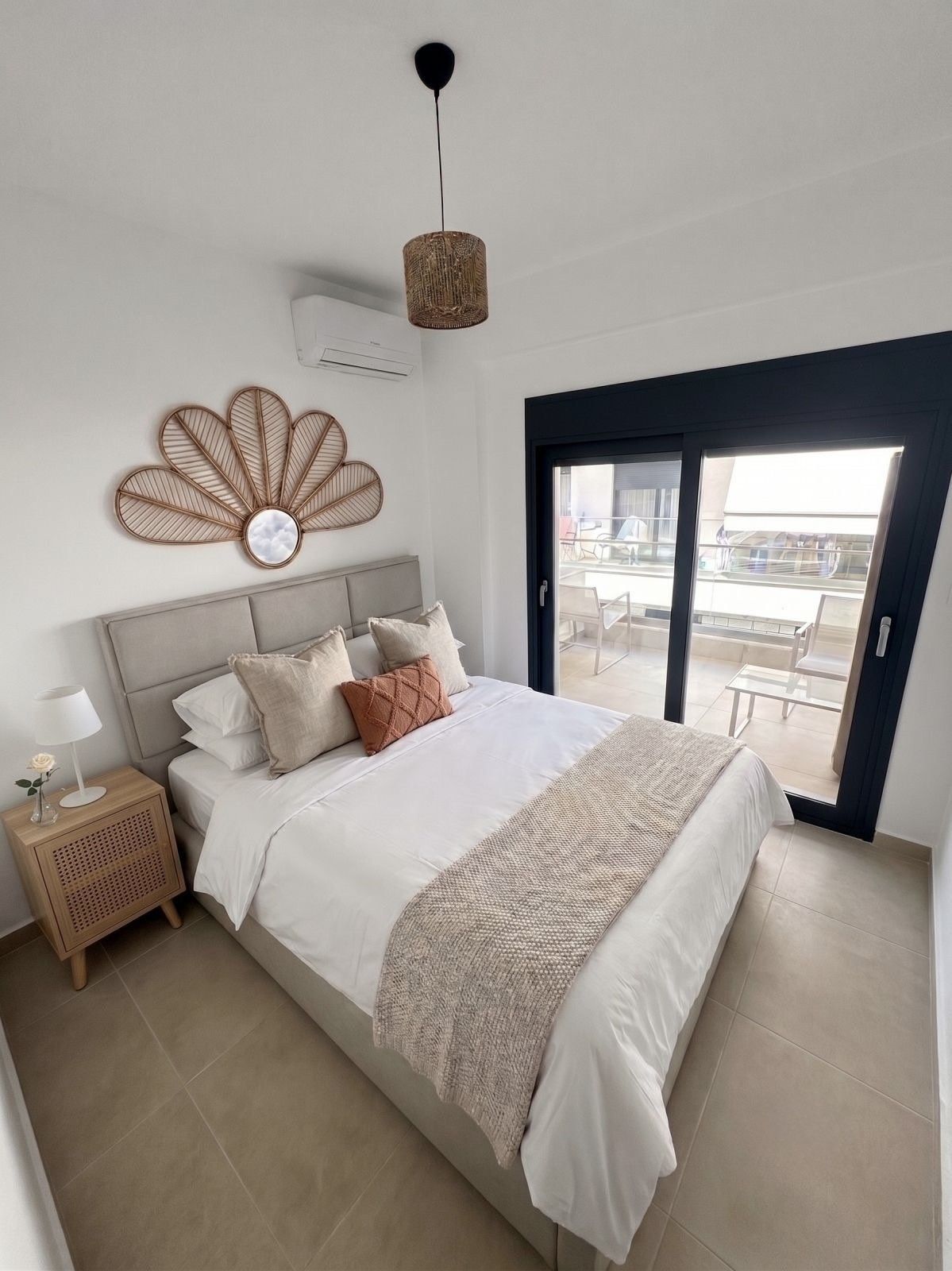 A bedroom with a bed, nightstand, lamp, and a decorative wall piece.