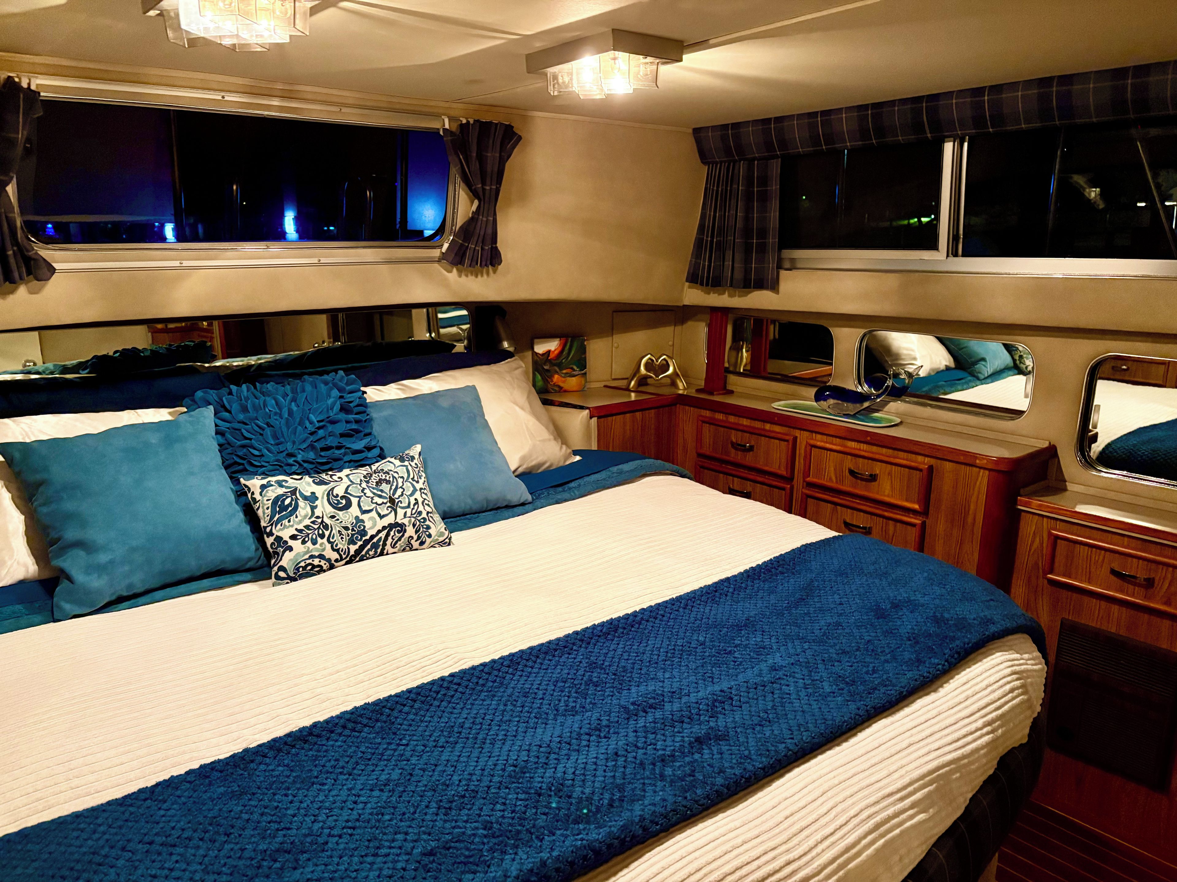 Une chambre à coucher avec un lit, des tables de chevet, une commode et une fenêtre avec des rideaux.