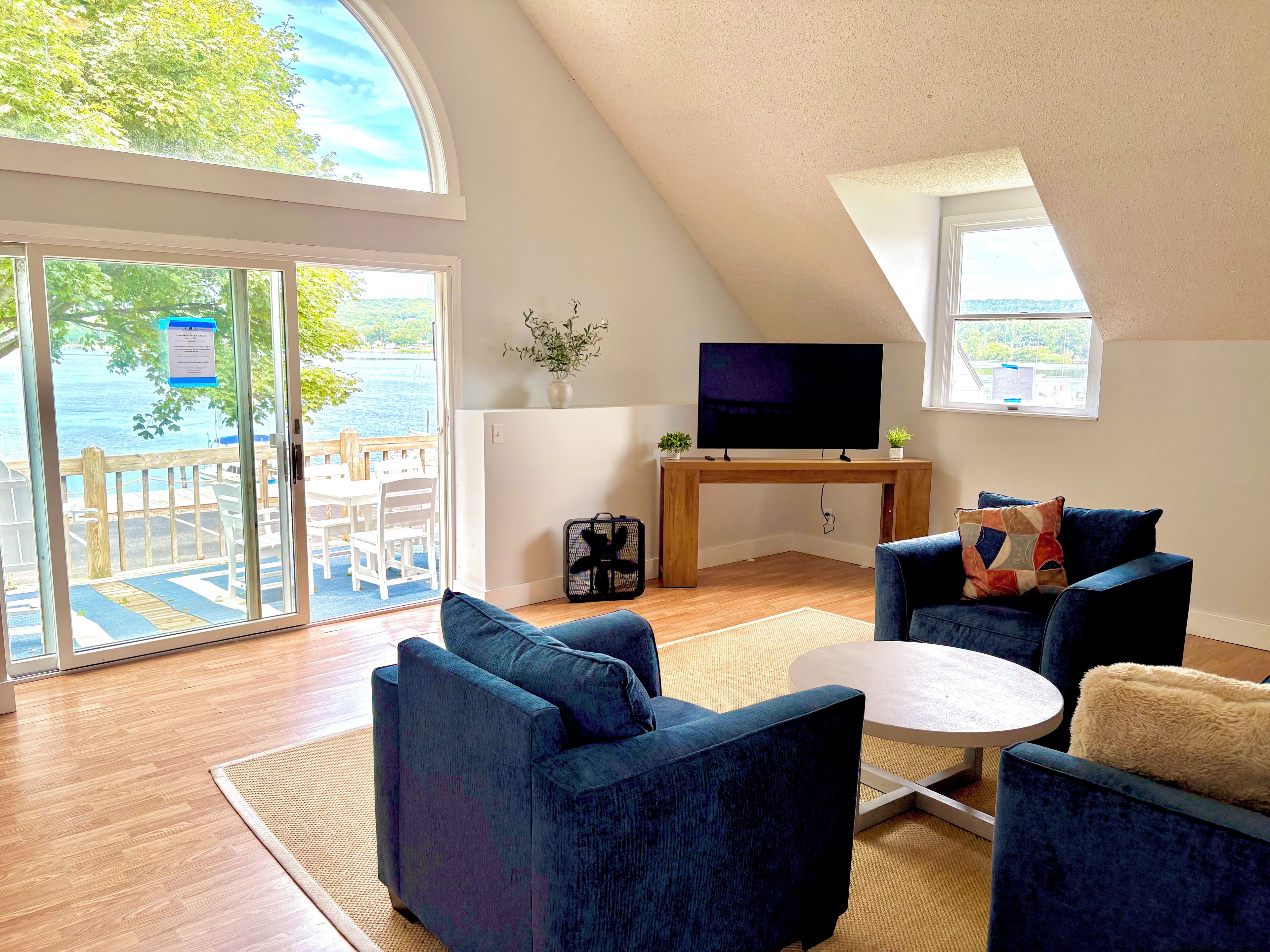 Un salón moderno con un televisor grande, asientos cómodos y vistas al exterior.