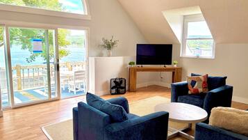 Un salón moderno con un televisor grande, asientos cómodos y vistas al exterior.