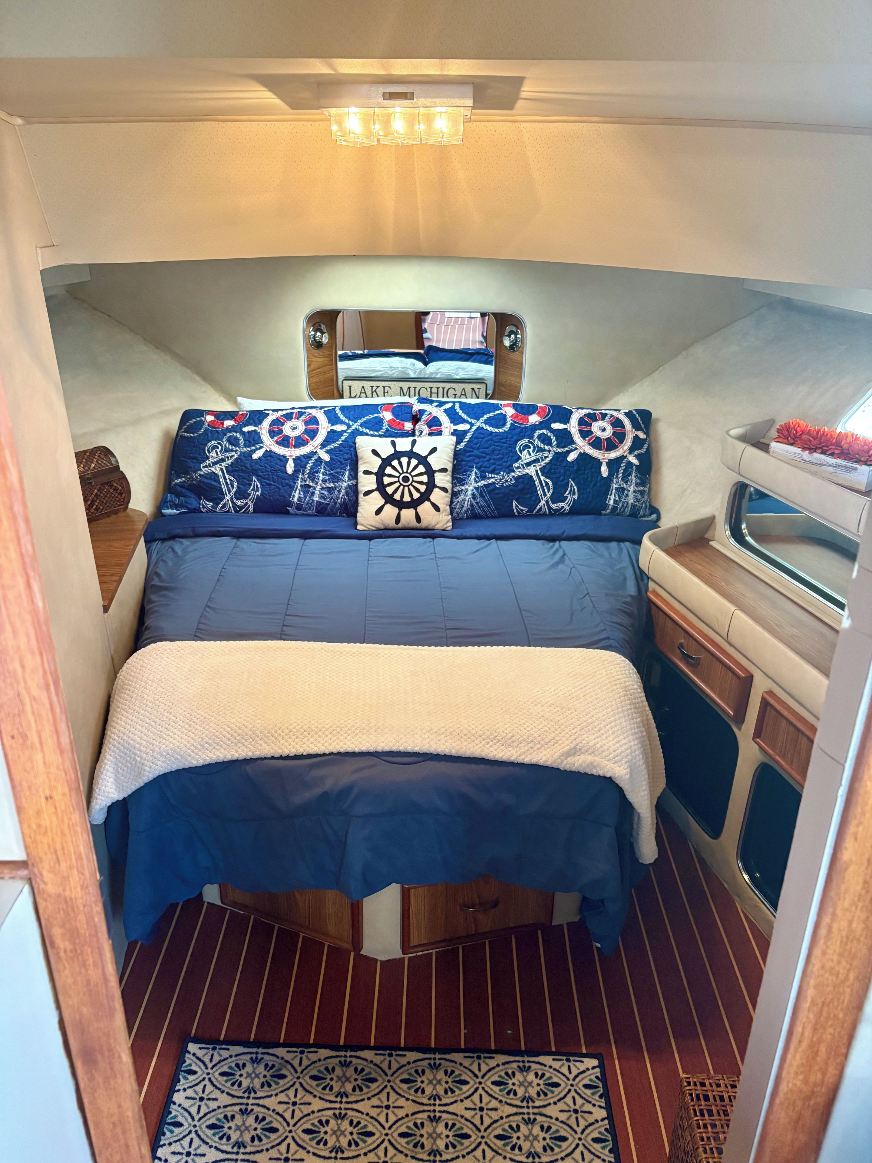 Une cabine compacte et bien éclairée, dotée d’un lit avec une literie aux motifs marins, d’une petite coiffeuse avec un miroir et d’une fenêtre.