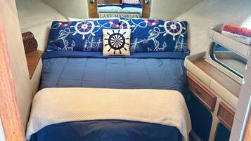 Une cabine compacte et bien éclairée, dotée d’un lit avec une literie aux motifs marins, d’une petite coiffeuse avec un miroir et d’une fenêtre.