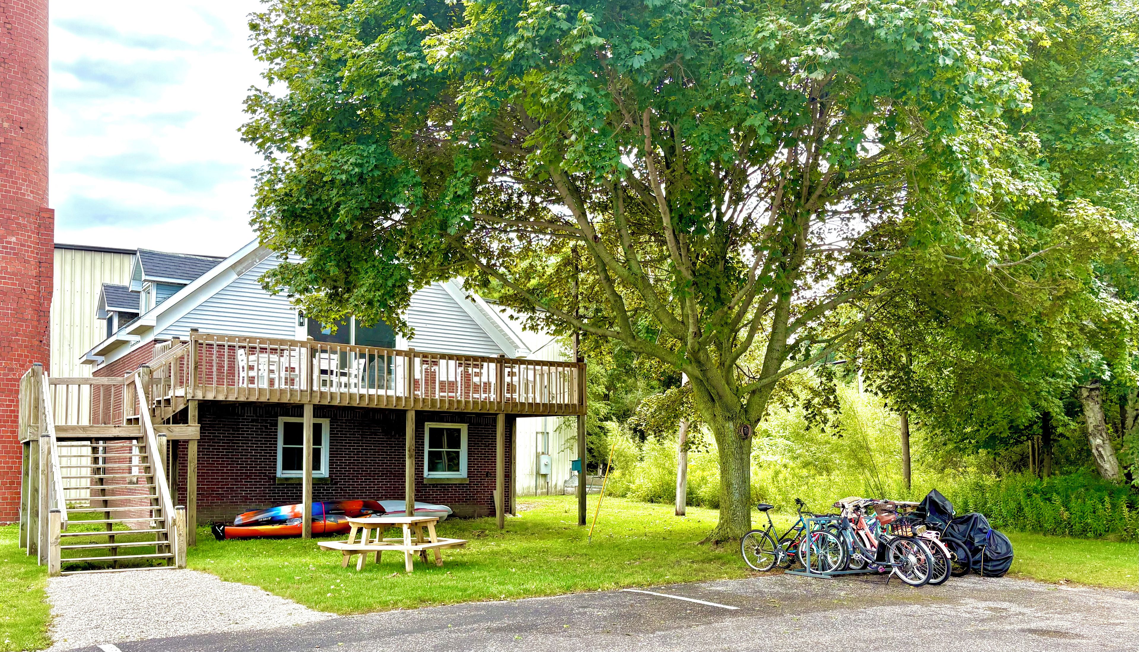 A house with a wooden deck, a picnic table, and a bicycle parked outside.