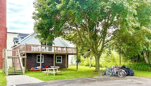 Une maison avec une terrasse en bois, une table de pique-nique et un vélo garé à l’extérieur.