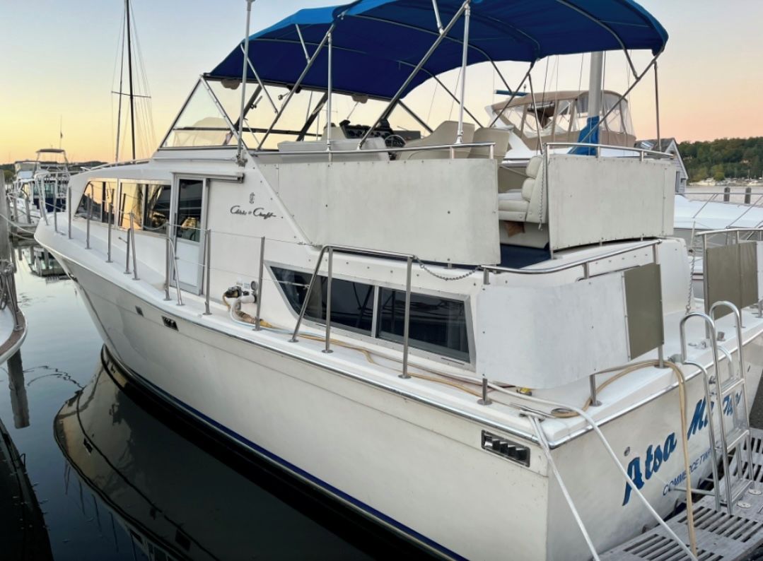 Un barco blanco con toldo azul, amarrado en un puerto deportivo.