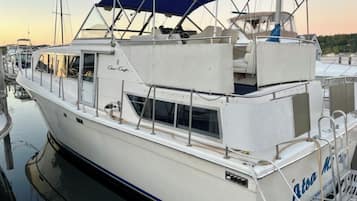 Un barco blanco con toldo azul, amarrado en un puerto deportivo.