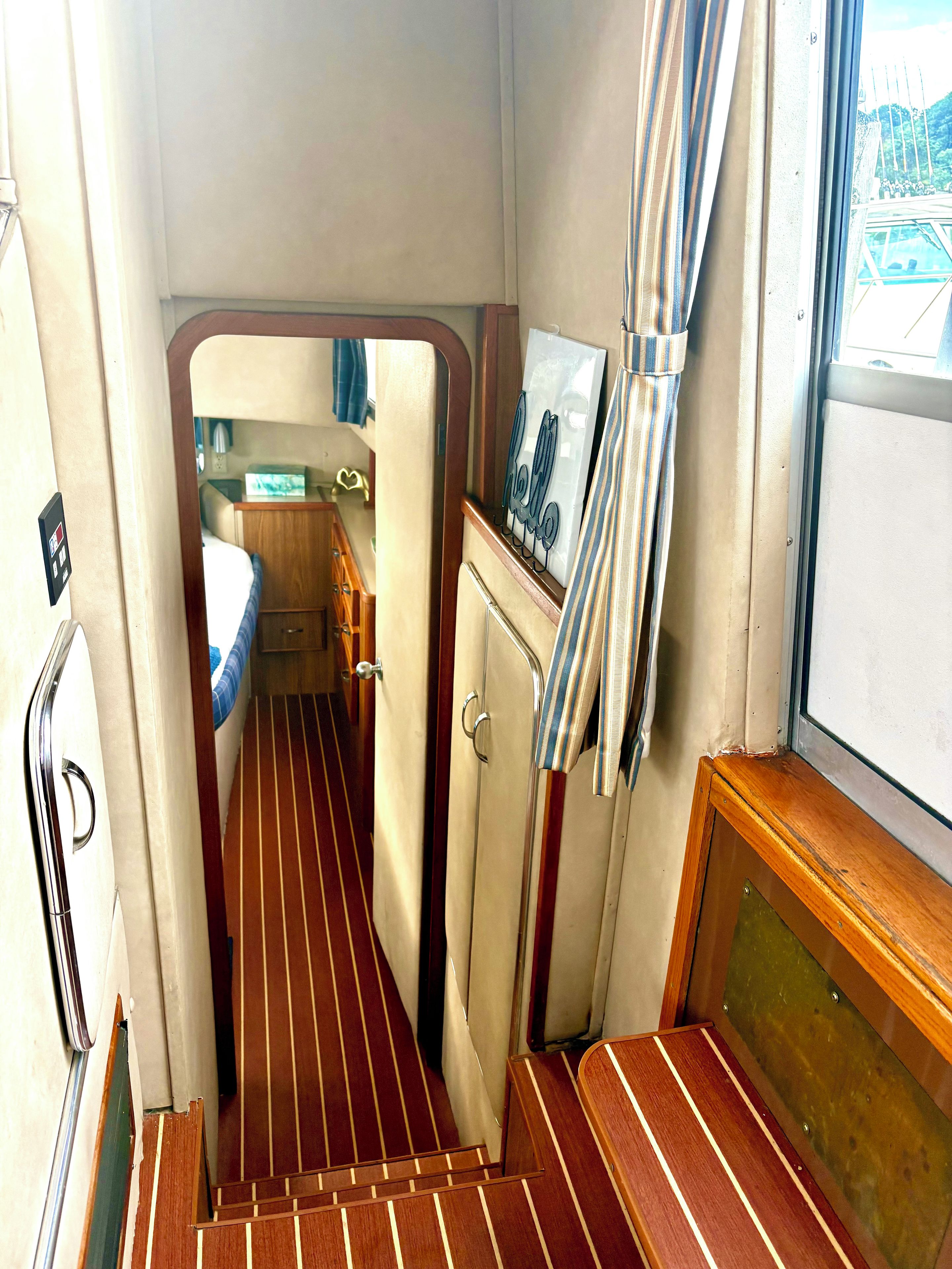 A narrow corridor with a wooden floor, a bed, and a small kitchenette area.