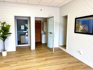 A room with wooden flooring, a potted plant, and a framed picture on the wall.