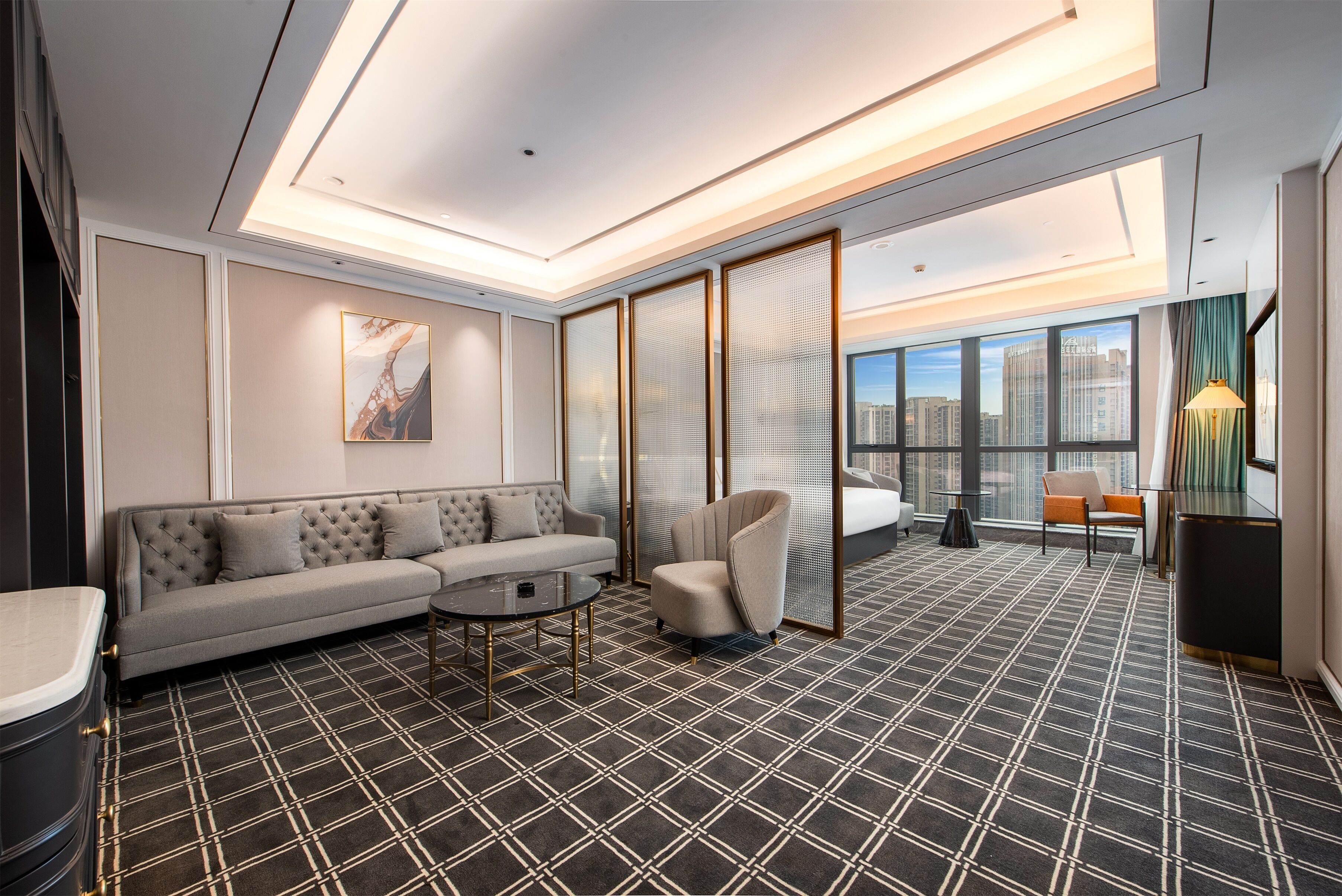 A modern hotel room with a sofa, armchair, and a small table.