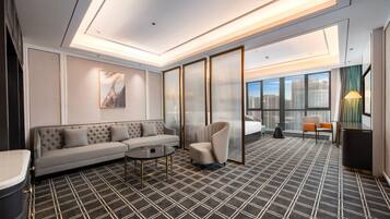 A modern hotel room with a sofa, armchair, and a small table.