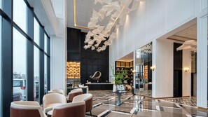 A hotel lobby with a reception desk, seating area, and a large window overlooking the city. - Xana Deluxe Hotel Foshan Jinbo Center (Foshan)