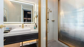 A modern bathroom with a large mirror, a sink, and a shower enclosure.