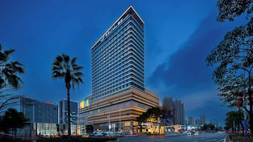A modern hotel with a prominent corner design, multiple floors, and a well-lit facade.