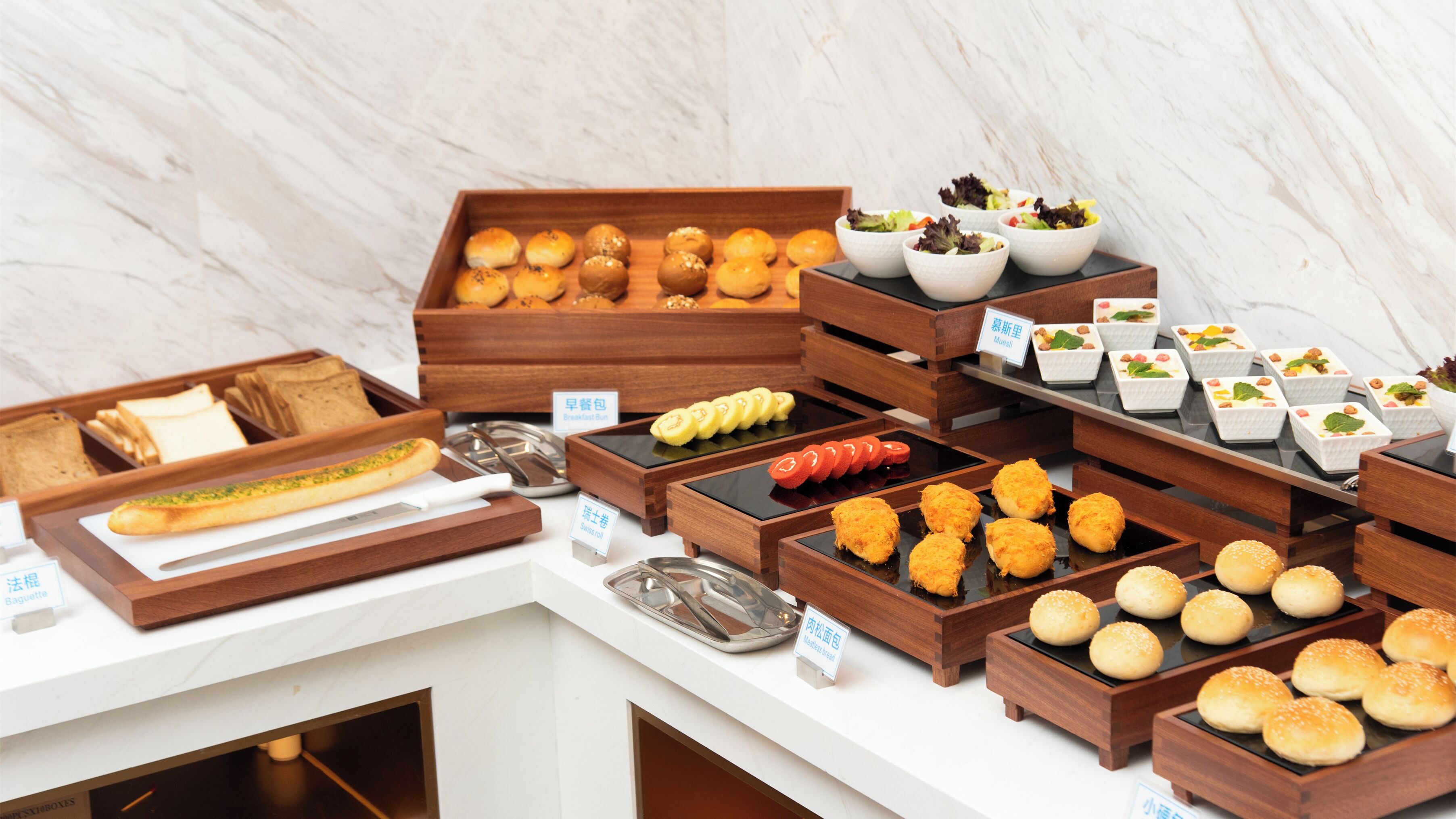 A buffet with various food items including bread, pastries, and salads.