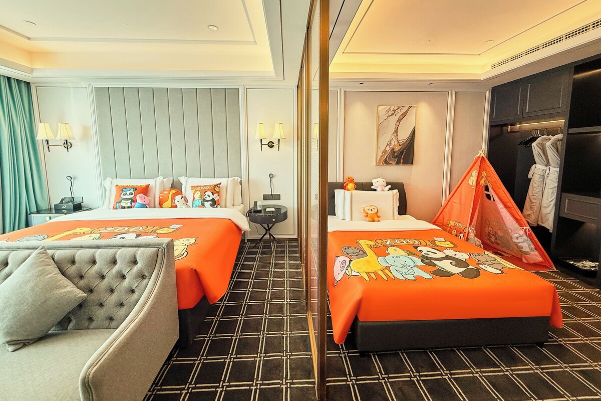A hotel room with two beds, a sofa, a mirror, a small table, and a wardrobe.
