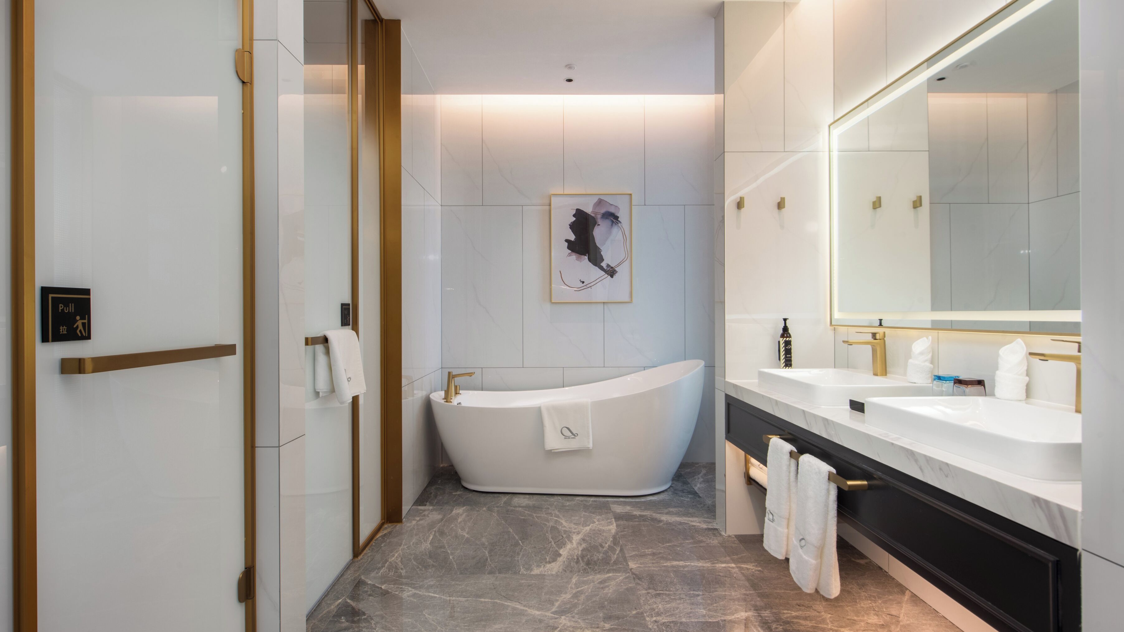 Un baño moderno con una bañera independiente, un espejo grande y una obra de arte enmarcada en la pared.