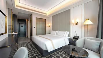 A hotel room with a bed, bedside table, lamp, chair, and a small table.