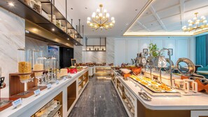 A modern breakfast buffet with a variety of food options, a central serving area, and a chandelier. - Xana Deluxe Hotel Foshan Jinbo Center (Foshan)
