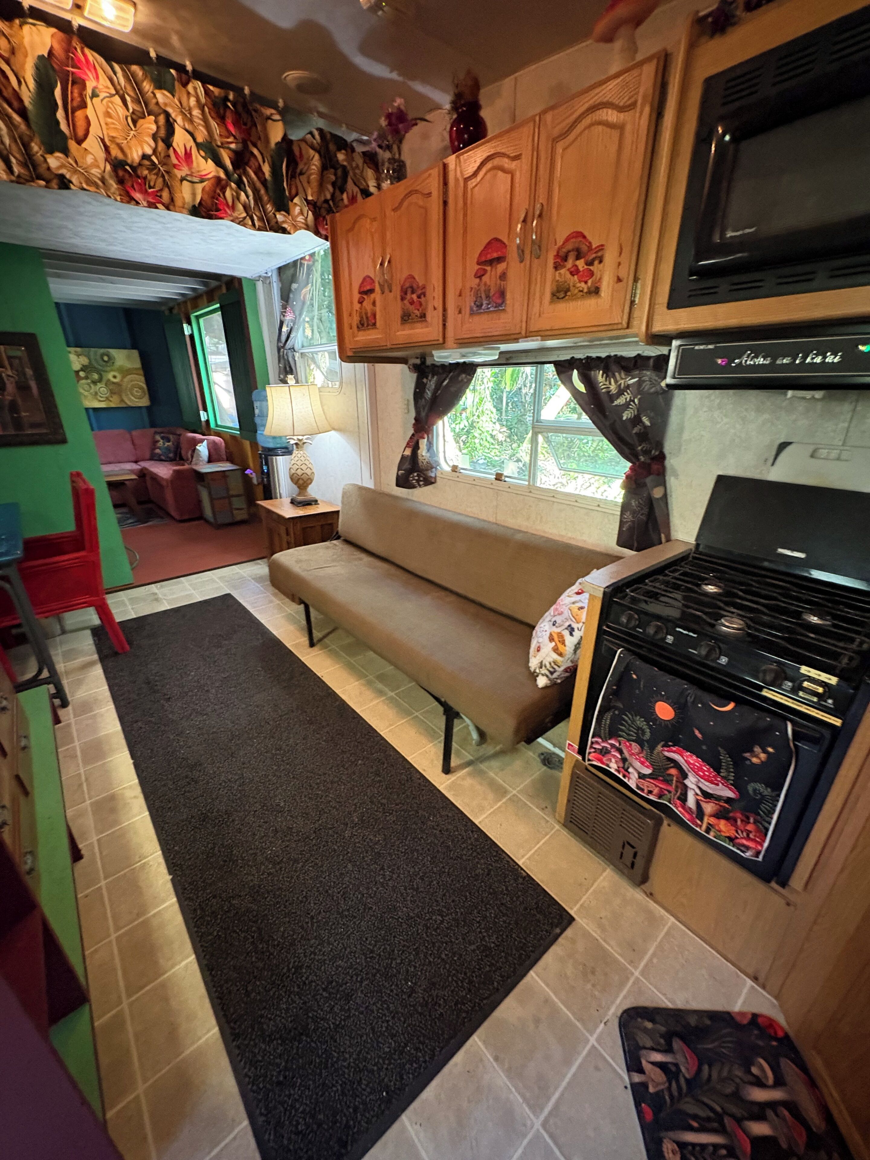 Une cuisine de taille réduite, équipée d’une cuisinière, d’un four à micro-ondes et de meubles de rangement en bois.