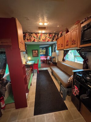 A compact kitchen with a stove, cabinets, and a dining area with a bench and chairs.