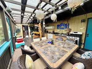 A cozy dining area with a large table, wicker chairs, and a view of the kitchen.