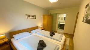Ein Hotelzimmer mit zwei Betten, einem Holzschrank, einem Badezimmer mit Spiegel und einem Bild an der Wand.