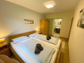 Ein Hotelzimmer mit zwei Betten, einem Holzschrank, einem Badezimmer mit Spiegel und einem Bild an der Wand.