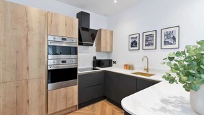 Una cucina moderna con elettrodomestici integrati, pavimento in legno a spina di pesce e un piano di lavoro in marmo bianco.