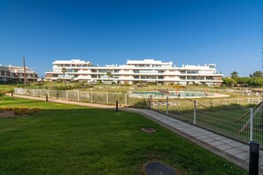 Een modern meerlaags woongebouw met een zwembad en een omheind tuin.