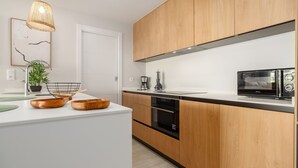 Eine moderne Küche mit Holzausstattung, einem Einbauofen und einer Mikrowelle.