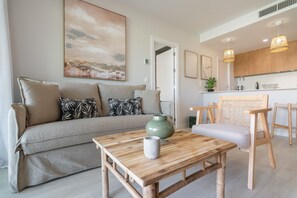 A modern living room with a sofa, a coffee table, and a painting on the wall. - Los Colibríes by H - Isla Canela Golf GLHC7002P104 (Ayamonte)