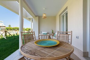 A covered outdoor seating area with a round table, two chairs, and a hanging light fixture. - Los Colibríes by H - Isla Canela Golf GLHC7002P104 (Ayamonte)
