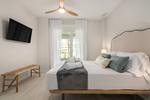 Ein Schlafzimmer mit einem Bett, einem Fernseher, einem Deckenventilator und einem Fenster mit Vorhängen.