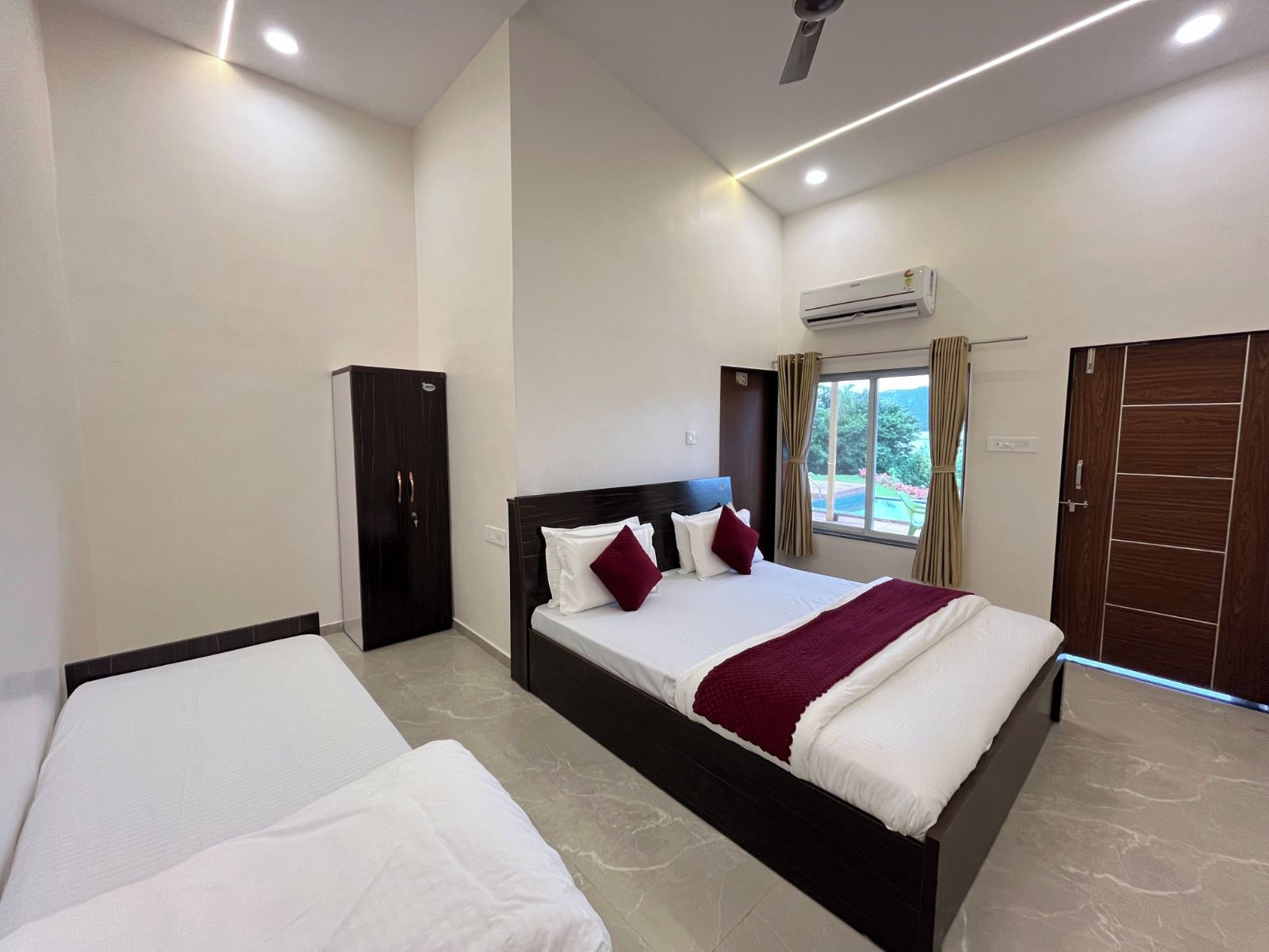 A hotel room with a bed, a wardrobe, and an air conditioning unit.