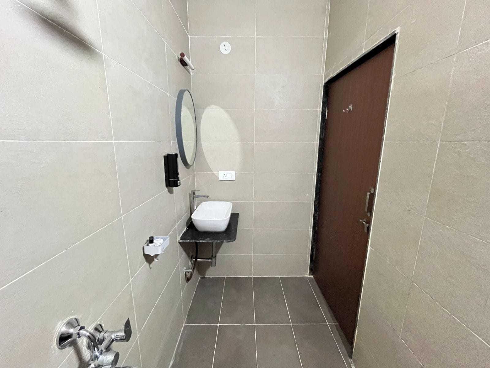 Un baño pequeño y estrecho con inodoro, lavamanos, espejo y dispensador de toallas.