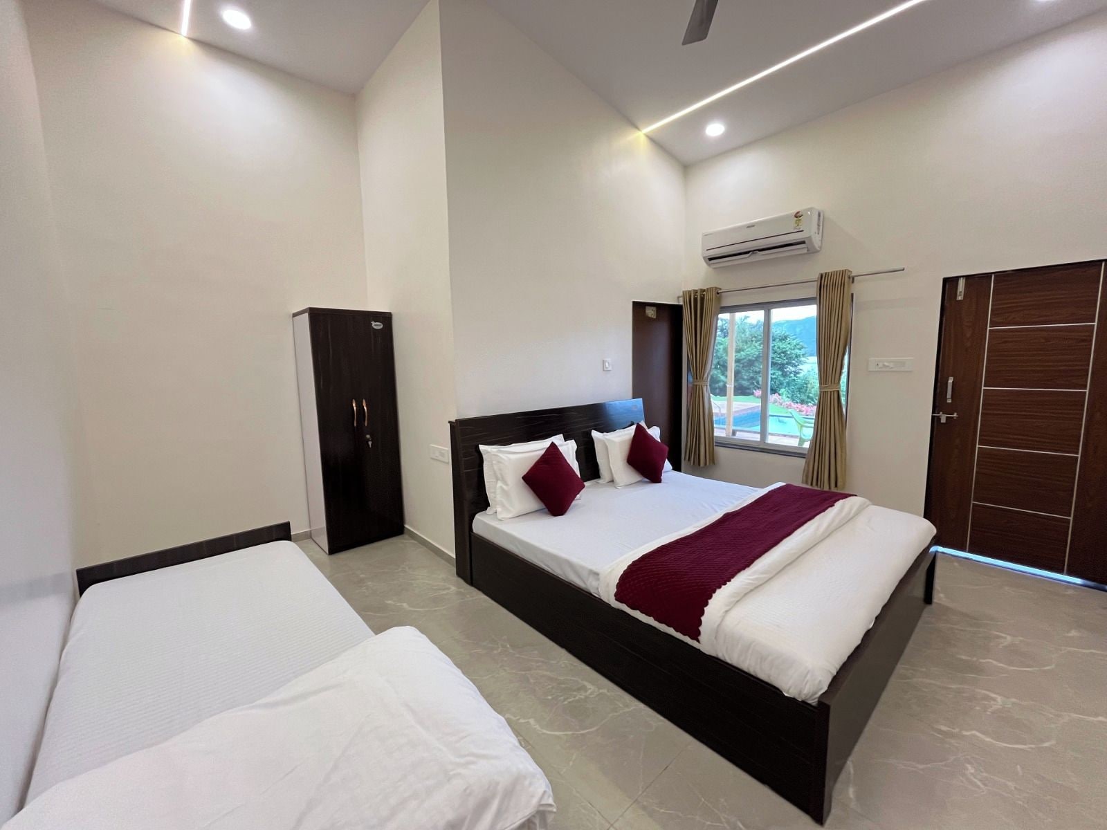 Une chambre d’hôtel avec un grand lit, une armoire, une fenêtre avec des rideaux et un appareil de climatisation.