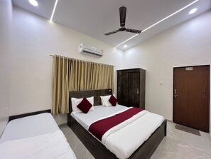 A hotel room with a bed, an air conditioning unit, a wardrobe, and a door.