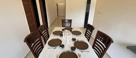 Un comedor con una mesa rectangular dispuesta para cuatro personas, rodeada de sillas de madera.